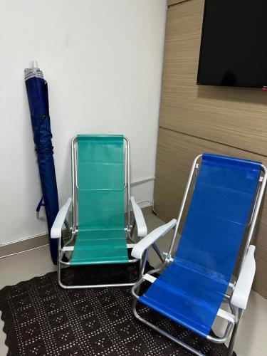 two empty chairs sitting in a room with a tv at Apto 50m da praia Gonzaguinha São Vicente Edifício Estrela do Mar in São Vicente