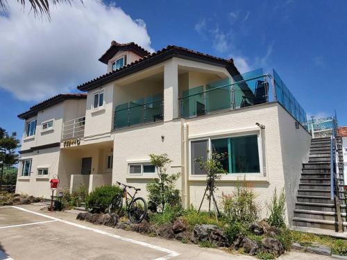 un edificio bianco con balcone sopra di Aewol Gwangryeong House a Jeju