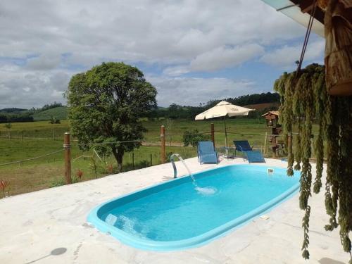 uma piscina num quintal com duas cadeiras e um guarda-sol em Casa Sítio Campo e Mar Balneário Picarras em Piçarras
