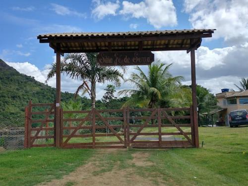a wooden gate with a sign in a field at Pousada na fazenda! Venha descansar! in Serra