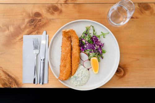 a white plate with food on a wooden table at Milford Sound Overnight Cruise - Fiordland Discovery in Milford Sound