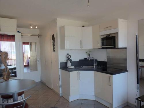 - une cuisine avec des placards blancs, un évier et une table dans l'établissement Résidence Héliopolis Bâtiment Fgh - Studio 2 couchages CAP d'AGDE MAE-4574, au Cap d'Agde