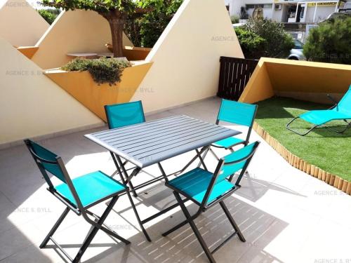 einen Tisch und vier Stühle auf einer Terrasse in der Unterkunft Résidence Héliopolis Bâtiment D - Appartements pour 2 Personnes 584 - Naturiste in Cap d'Agde