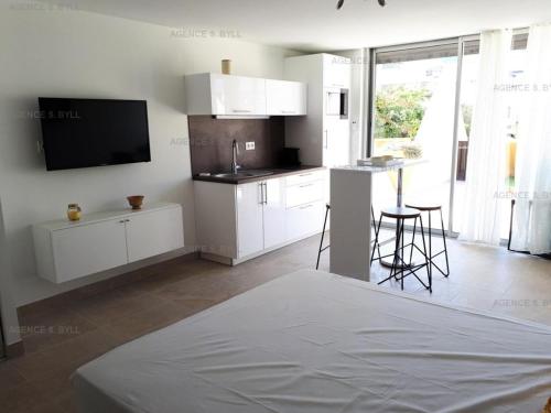 eine Küche mit weißen Schränken und einem TV an der Wand in der Unterkunft Résidence Héliopolis Bâtiment D - Appartements pour 2 Personnes 584 - Naturiste in Cap d'Agde