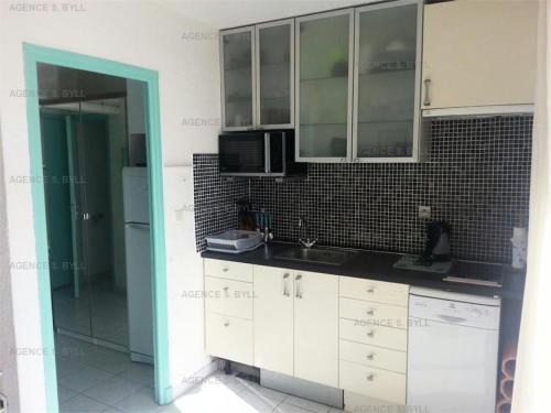 une cuisine avec des armoires blanches et un micro-ondes dans l'établissement Résidence Héliopolis Bâtiment C - Héliopolis Bât. C studio 2 Pers. MAE-5474, au Cap d'Agde