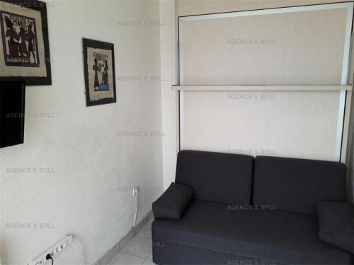 - un salon avec un canapé et des photos sur le mur dans l'établissement Résidence Héliopolis Bâtiment C - Héliopolis Bât. C studio 2 Pers. MAE-5474, au Cap d'Agde