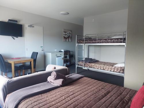 1 dormitorio con 2 literas y escritorio en Northpark Motel en Timaru