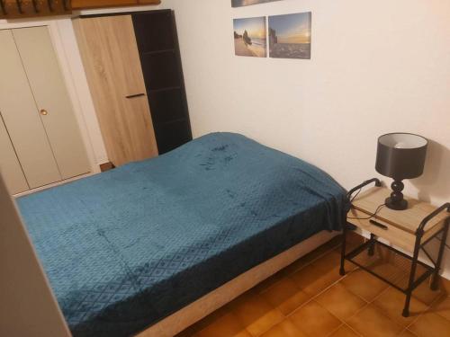 een kleine slaapkamer met een blauw bed en een stoel bij Résidence Héliovillage - Maisons & Villas pour 4 Personnes 944 - Naturiste in Cap d'Agde