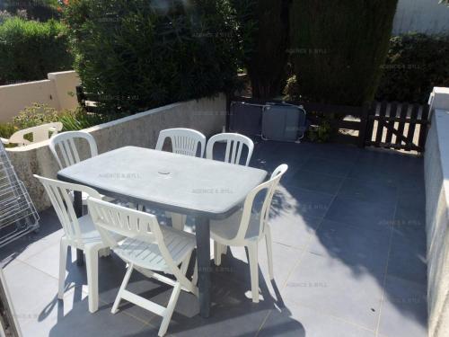 une table blanche et des chaises assises sur une terrasse dans l'établissement Résidence Héliovillage - VILLA 4 couchages CAP d'AGDE MAE-2804, au Cap d'Agde