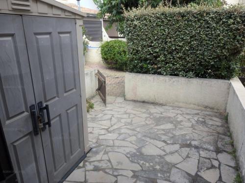 una entrada a un garaje con una puerta y una pasarela de piedra en Résidence Héliovillage - Maisons & Villas pour 4 Personnes 804 - Naturiste, en Cap d'Agde