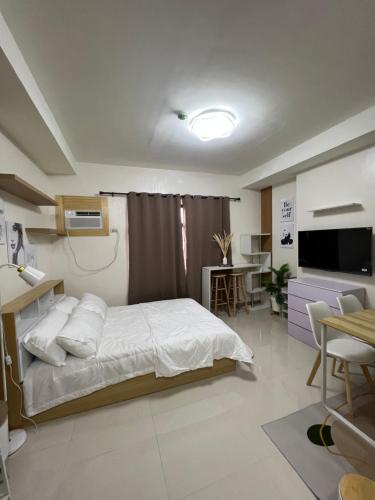 1 dormitorio con cama, mesa y TV en Kristinas Homestay- Cozy Resort Vibe Condotel, en Cebú