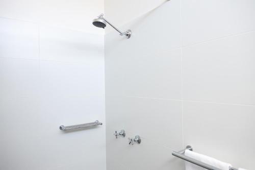 a bathroom with white walls and chrome fixtures at The Club Hotel in Gladstone