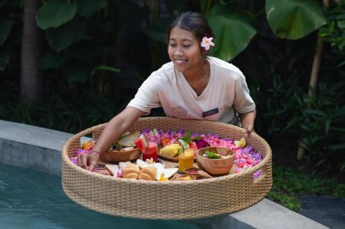 une femme assise à côté d'un grand panier de nourriture dans l'établissement Sanctuary Villas, à Ubud