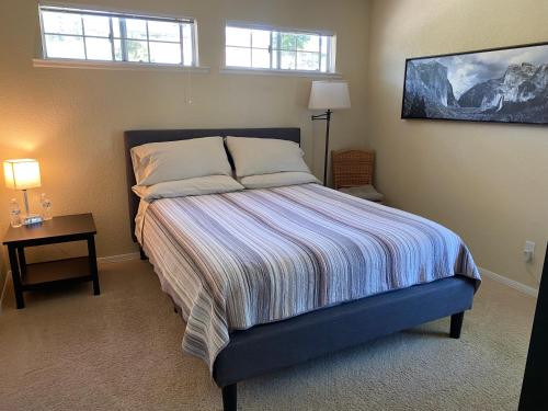 ein Schlafzimmer mit einem Bett, einem Tisch und zwei Fenstern in der Unterkunft Oak Retreat by Yosemite National Park in Coarsegold