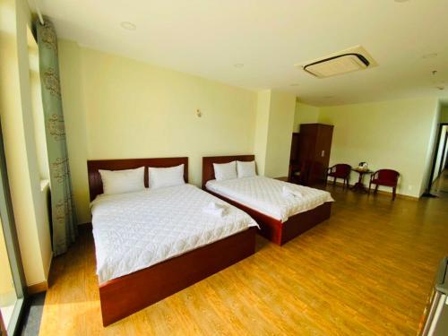 um quarto com 2 camas, uma mesa e cadeiras em Dũng India Hotel em Cidade de Ho Chi Minh
