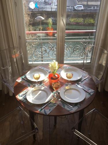 une table avec trois plaques et une fenêtre dans l'établissement Paris, au bord du Canal Saint Martin, à Paris