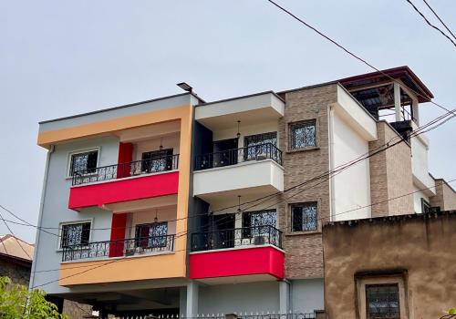 ein Apartmenthaus mit roten und weißen Balkonen in der Unterkunft Residence Ethan Nji - Tropical Paradise in Jaunde