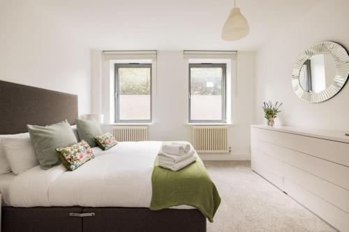 1 dormitorio blanco con 1 cama grande y espejo en Wild Roses Serviced Apartments - Borough, en Londres