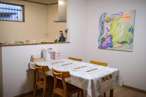 a kitchen with a table with chairs and a painting at 难波站 高岛屋步行5分钟 双层独栋别墅150平 4卧室3厕所2浴室 空间宽敞设施齐全 八阪神社步行1分钟 心斋桥 道顿堀 黑门市场 通天阁步行圈内 in Osaka