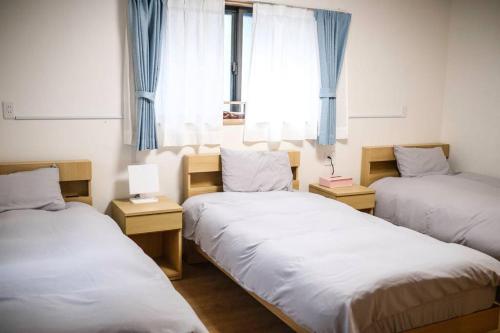 a room with three beds and a window at 难波站 高岛屋步行5分钟 双层独栋别墅150平 4卧室3厕所2浴室 空间宽敞设施齐全 八阪神社步行1分钟 心斋桥 道顿堀 黑门市场 通天阁步行圈内 in Osaka