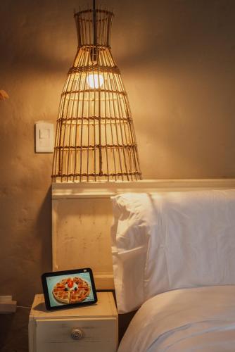 a clock on a night stand next to a bed with a lamp at Cocli Hotel Boutique Salento in Salento