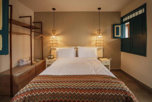 a bedroom with a large bed and two lights at Cocli Hotel Boutique Salento in Salento