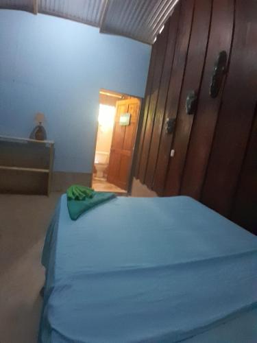 a bedroom with a blue bed and a wooden door at Los Paniquines Ecolodge in Drake