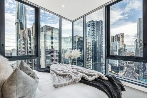 a bedroom with a large window with a city view at VAQUAY Panorama In Southbank in Melbourne