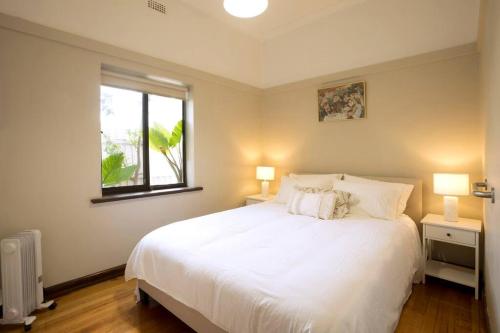 - une chambre avec un grand lit blanc et une fenêtre dans l'établissement Richmond Delights - 4 Bedrooms and a Big Backyard, à Melbourne