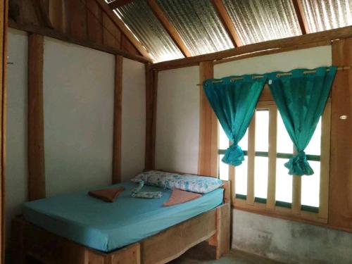 ein kleines Bett in einem Zimmer mit Fenster in der Unterkunft Cabinas casa Jungla in Drake