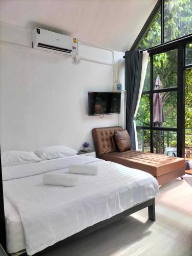 a white bedroom with a large bed and a chair at p.p. hill & house in Ban Tha Phae