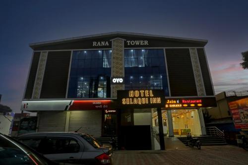 a building with cars parked in a parking lot at Townhouse Hotel Selaqui Inn in Jhājra