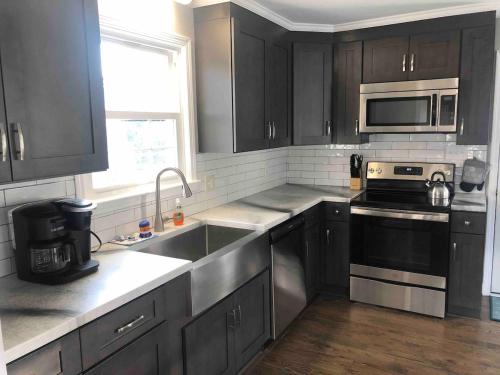 una cocina con armarios negros y electrodomésticos de acero inoxidable en Heart Of Hickory #1 Comfy & Clean, 3br2ba Apt, en Hickory