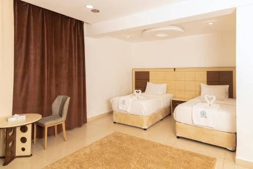 1 dormitorio con 2 camas, mesa y silla en Diamond Star Hotel فندق النجمة الماسية en Seeb