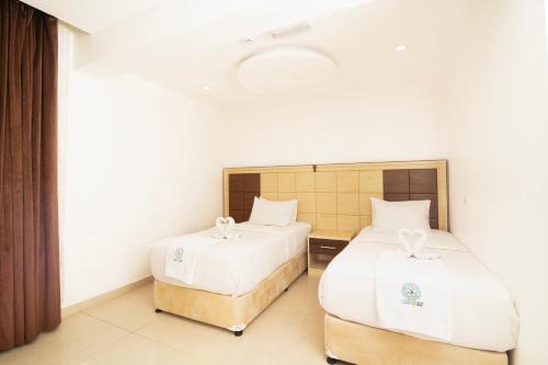 a bedroom with two beds with white sheets at Diamond Star Hotel فندق النجمة الماسية in Seeb