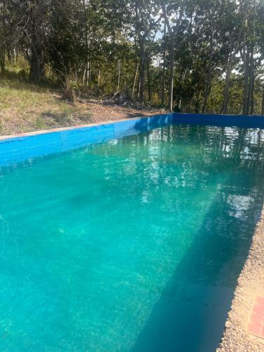 ein Pool mit blauem Wasser und Bäumen im Hintergrund in der Unterkunft Finca La Esperanza - Cabaña Villa Marujita in Socorro