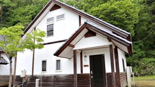 a white house with a black door and trees at Tabino Camping Base Kami Yuland - Vacation STAY 52574v in Osaki
