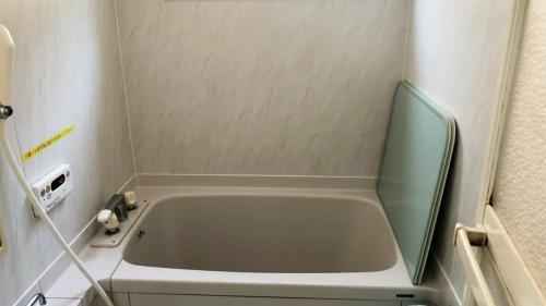 een kleine badkamer met een bad in de hoek bij Tabino Camping Base Kami Yuland - Vacation STAY 52575v in Osaki