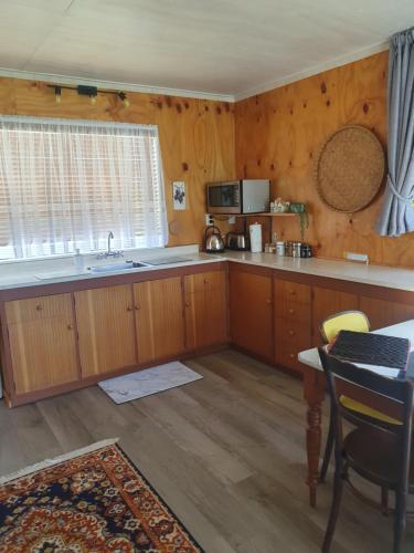 cocina con armarios de madera, mesa y ventana en Mangaroa, farmstay en Upper Hutt