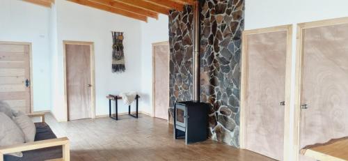 sala de estar con pared de piedra y chimenea en Gran Cabaña con tinaja privada, Curacautín C en Curacautín