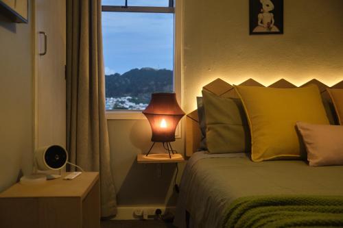 a bedroom with a bed with a lamp next to a window at Central Nest- view & style in Wellington