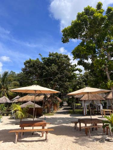 a group of picnic tables and umbrellas on a beach at Marika Resort in Badian