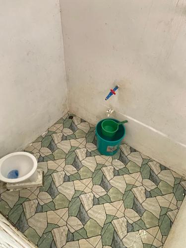 a bathroom with a toilet and a green bucket at Ocam Ocam Casadyan Inn in New Busuanga