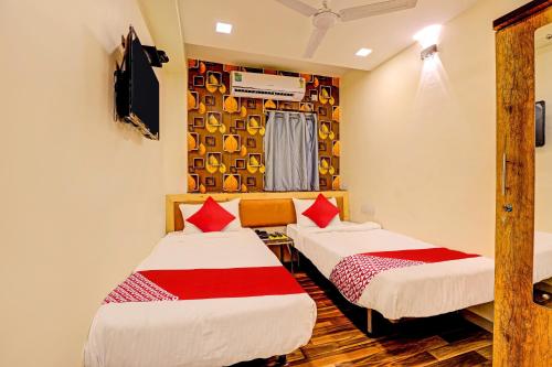 a room with two beds and a tv at Hotel Alexa in Ahmedabad