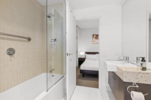 łazienka z prysznicem, umywalką i łóżkiem w obiekcie Sleek 2-Bed City High-Rise with Amenities w Melbourne