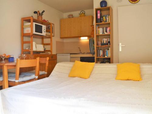 - une chambre avec un grand lit blanc et des oreillers jaunes dans l'établissement T2 cabine avec loggia, proche plage et commerces, parking inclus - Bormes-les-Mimosas - FR-1-251-521, à Bormes-les-Mimosas