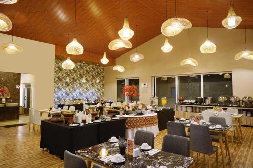 un comedor con mesas, sillas y luces en Front One Hotel Sragen, en Sragen