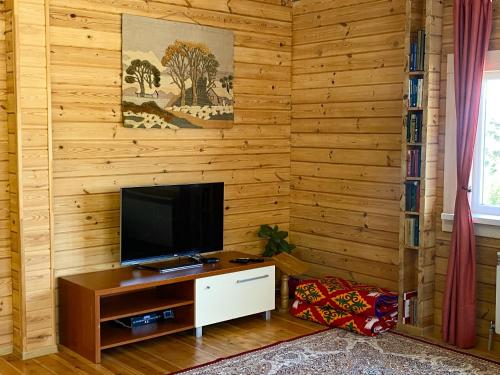 een woonkamer met een televisie aan een houten muur bij Милая квартира премиум класса in Alma-Ata