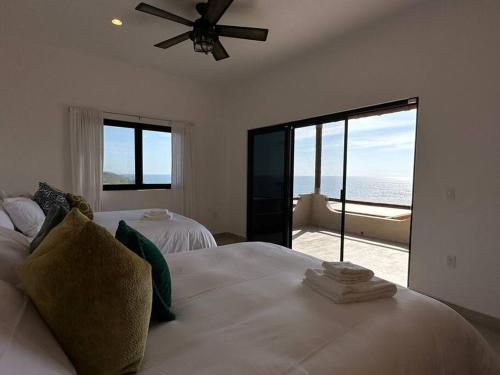 a bedroom with two beds and a ceiling fan at Villa Tres Vistas. in El Pescadero