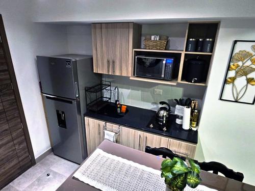 uma pequena cozinha com um frigorífico de aço inoxidável em Nuevo y Moderno apartamento en la atractiva Zona 4 em Guatemala